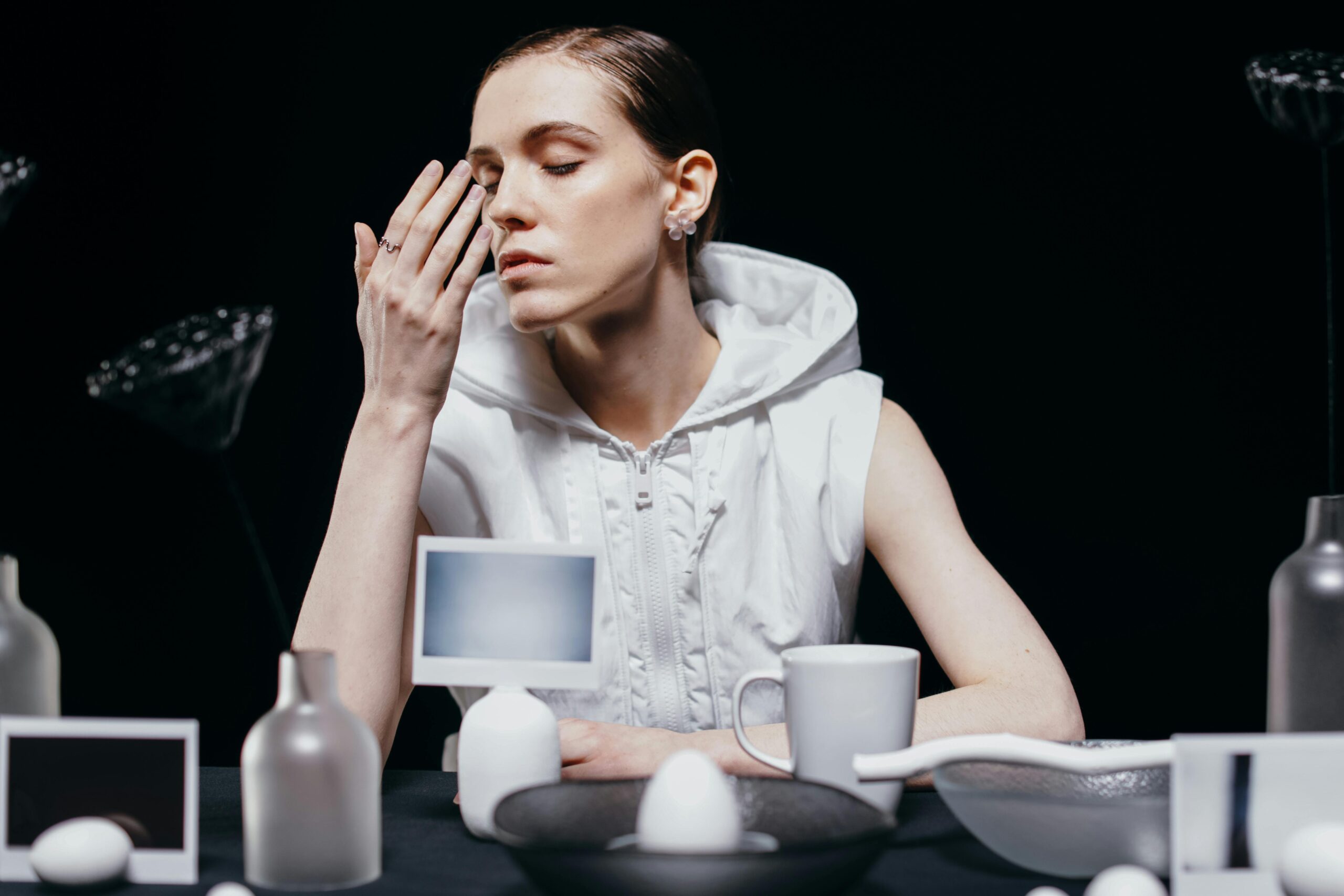 A serene portrayal of a woman seated at a table with monochrome elements, capturing a moment of introspection.