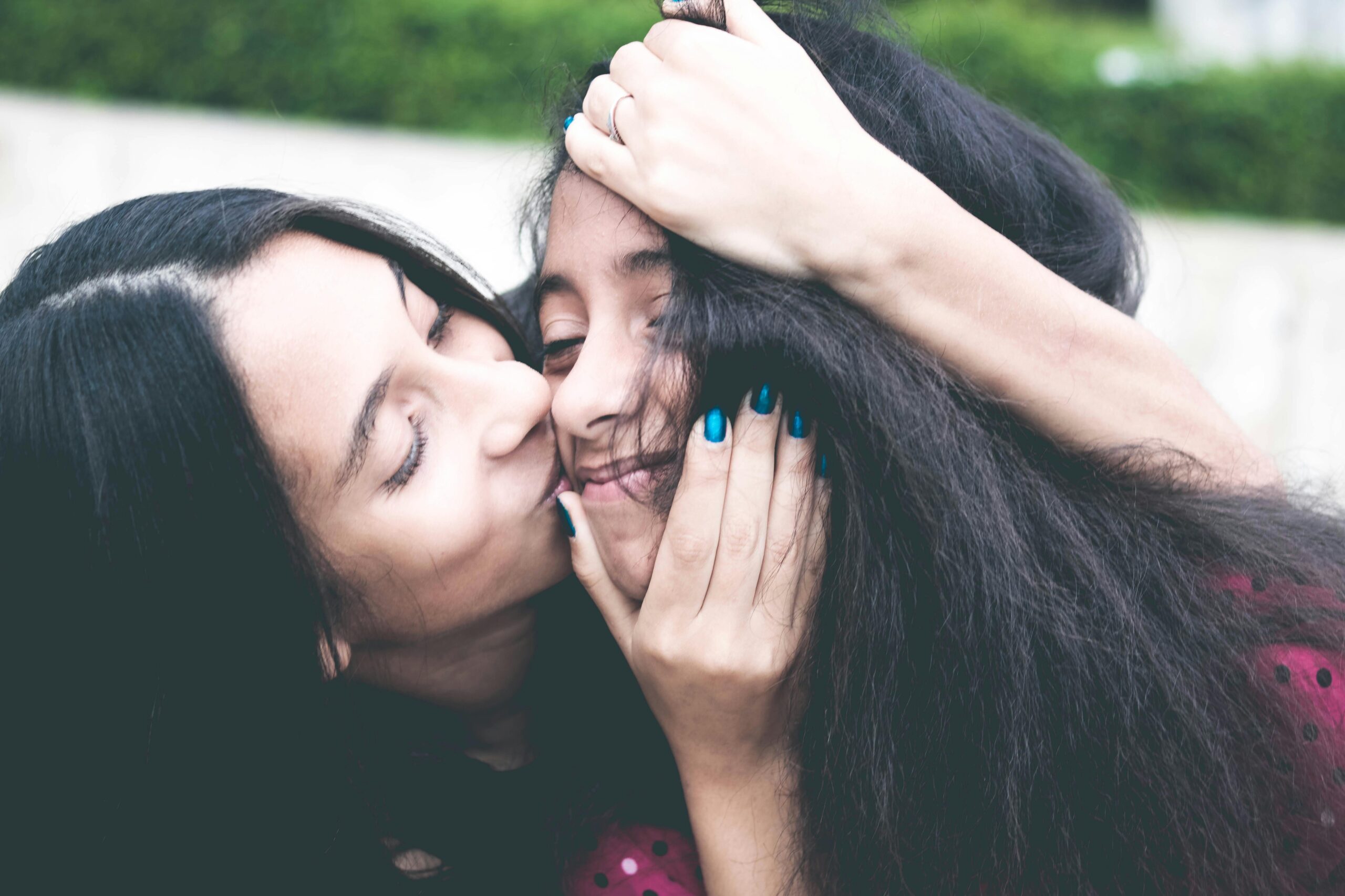 A mother and daughter share a loving embrace outdoors, capturing a tender family moment full of warmth and happiness.