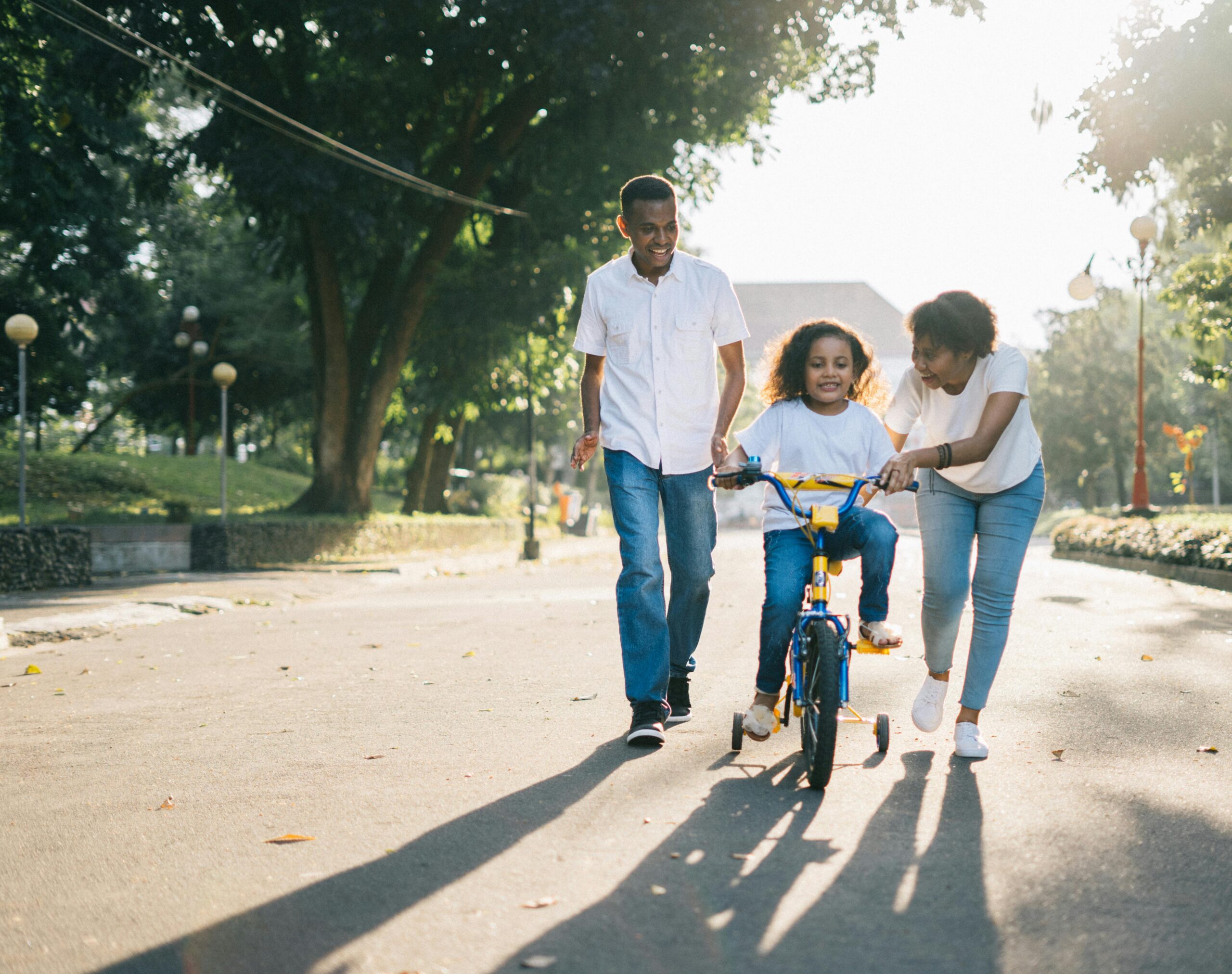 Happy family teaching their child to cycle on a sunny day outdoors.