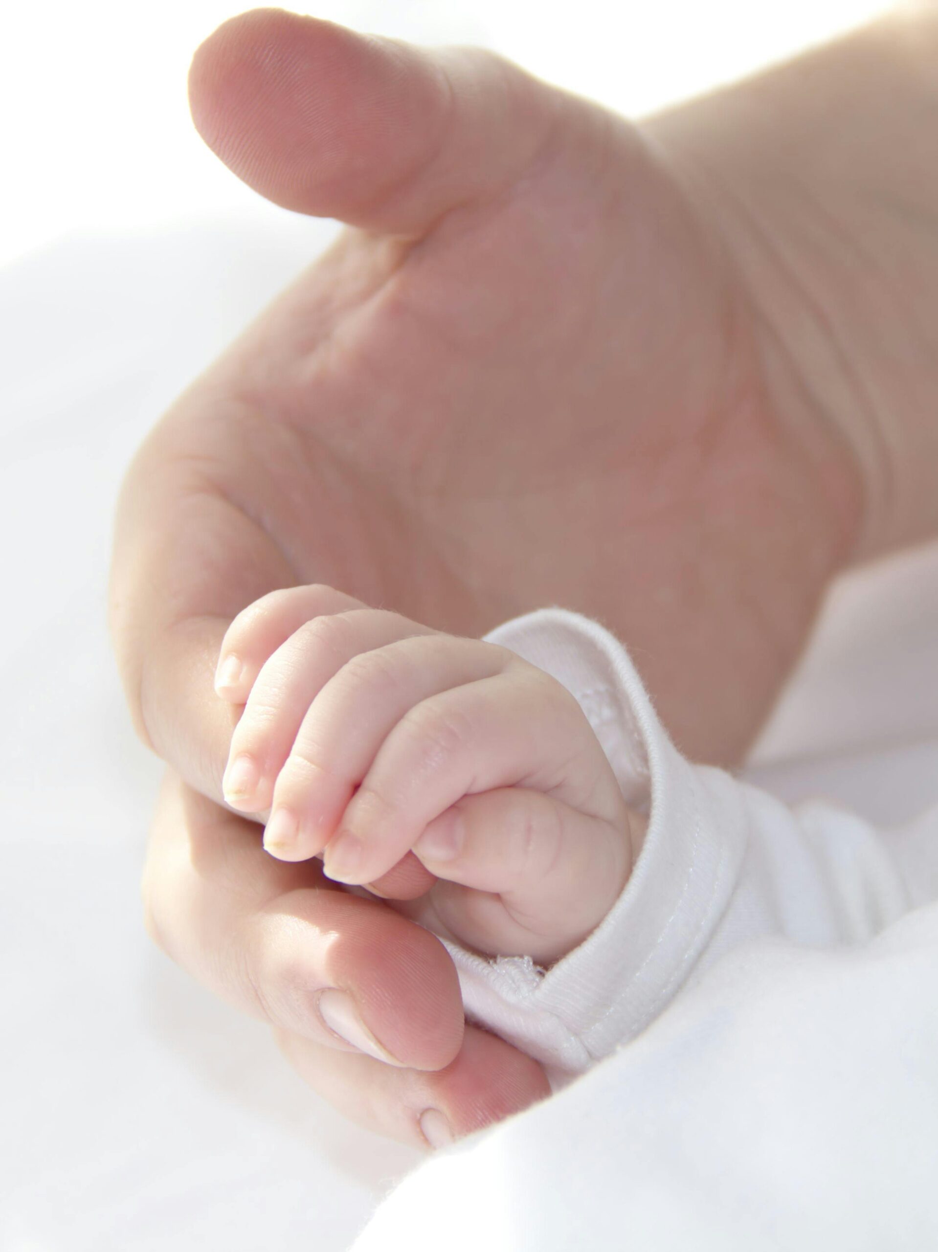 A serene and intimate photo of a baby holding an adult's hand, symbolizing love and connection.