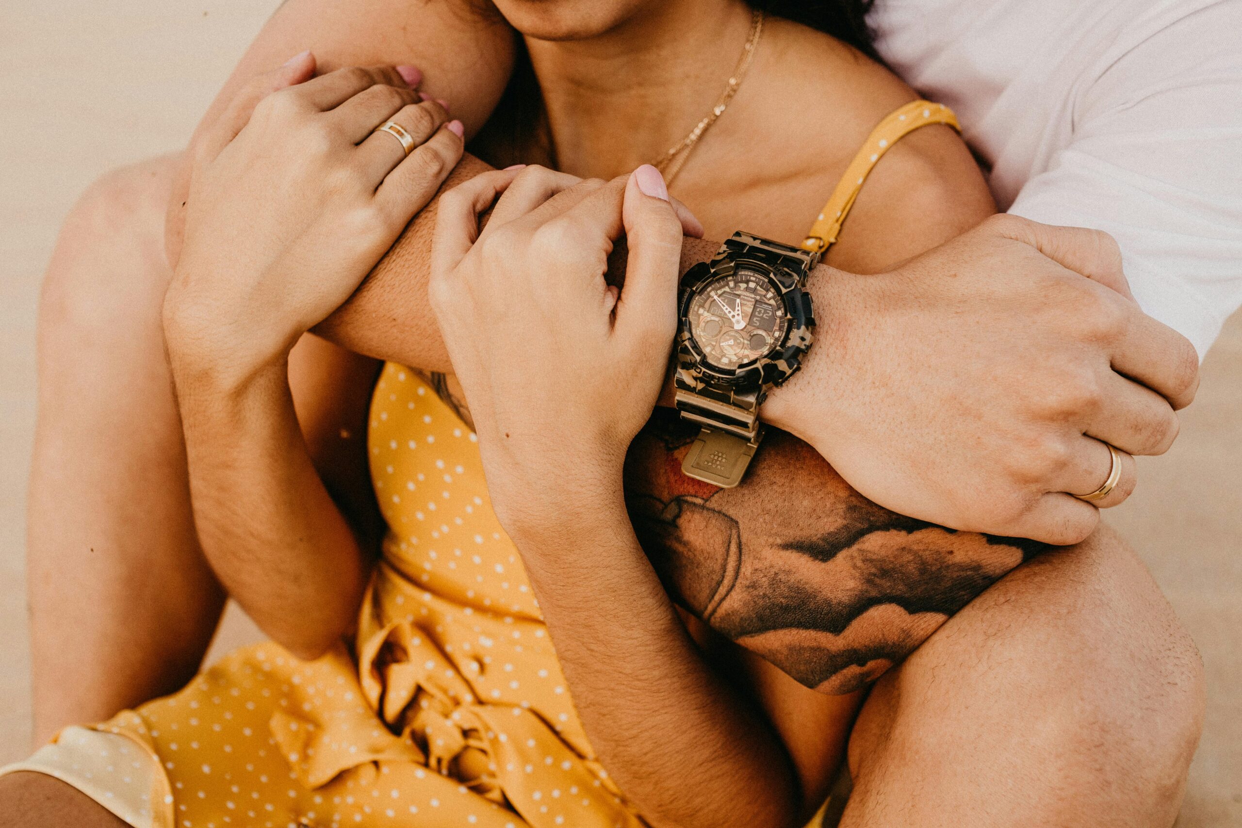 Warm, intimate close-up of a couple embracing, highlighting a stylish wristwatch.