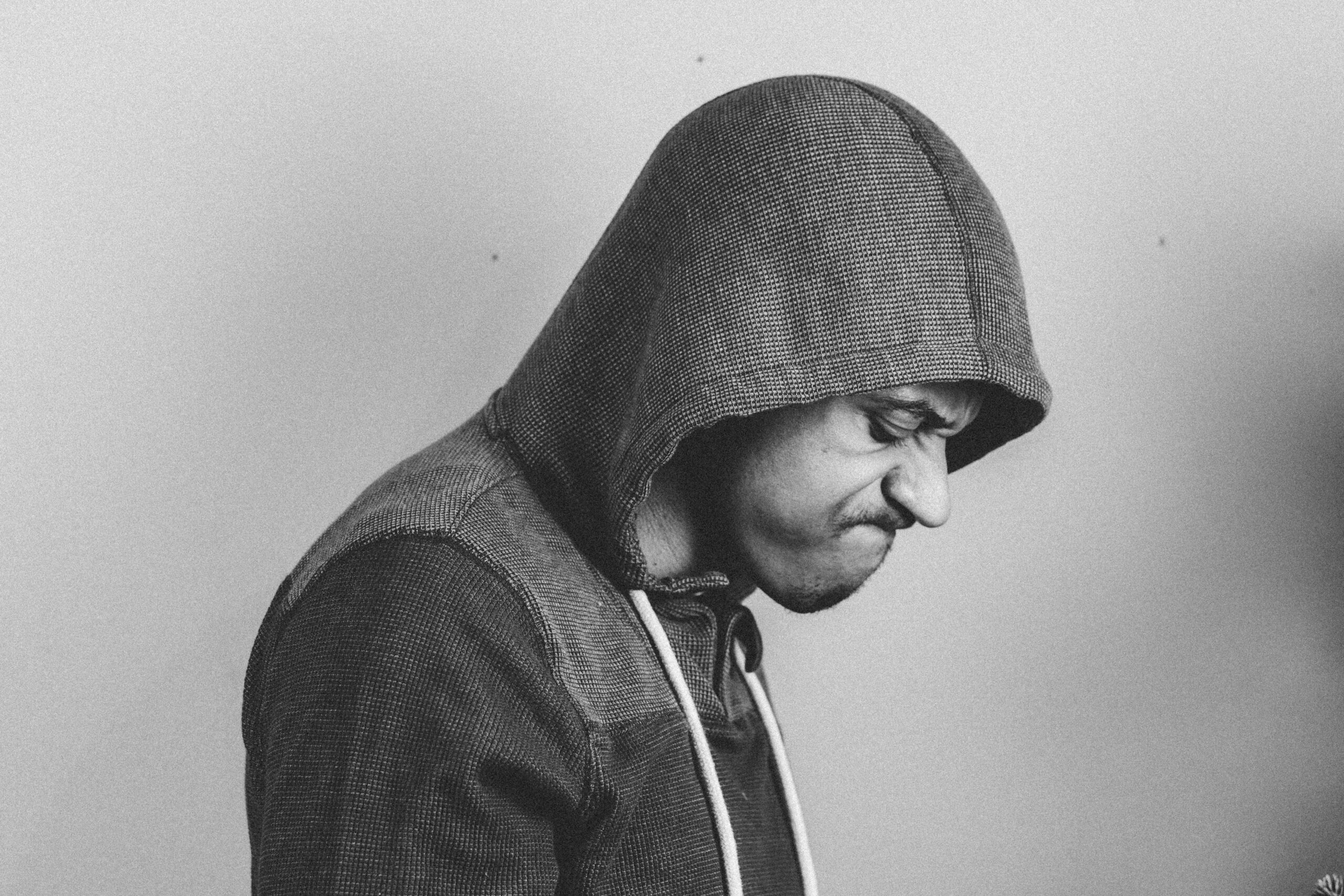 Black and white portrait of a man in a hoodie, expressing frustration.