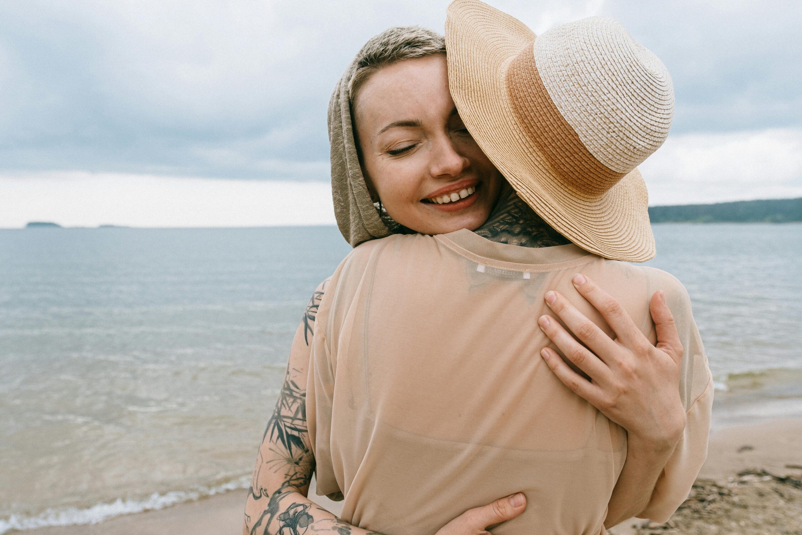 Two women embracing on a serene beach, expressing joy and friendship.