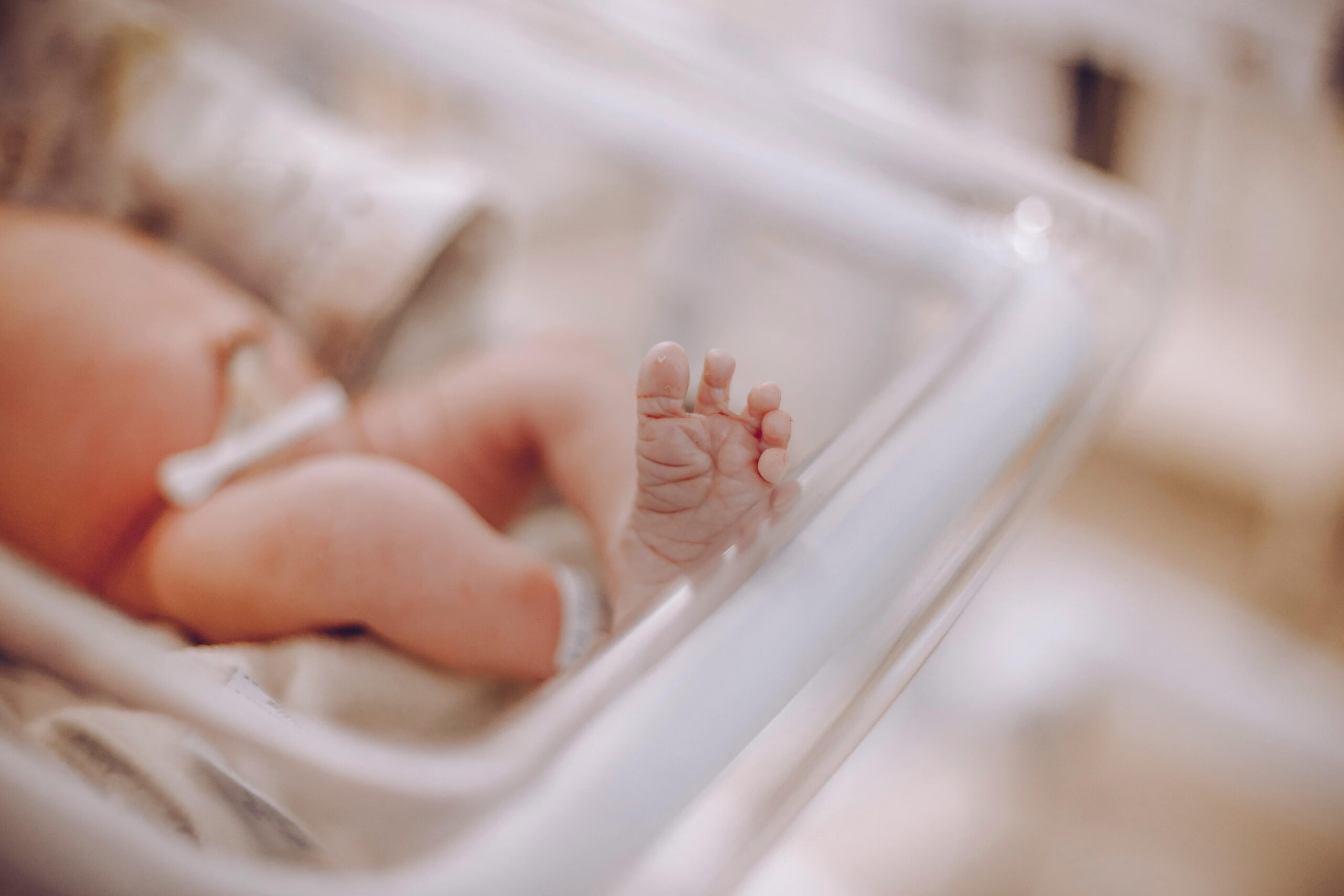 Close-up of a newborn's foot in a hospital cradle, capturing the tenderness of new life.