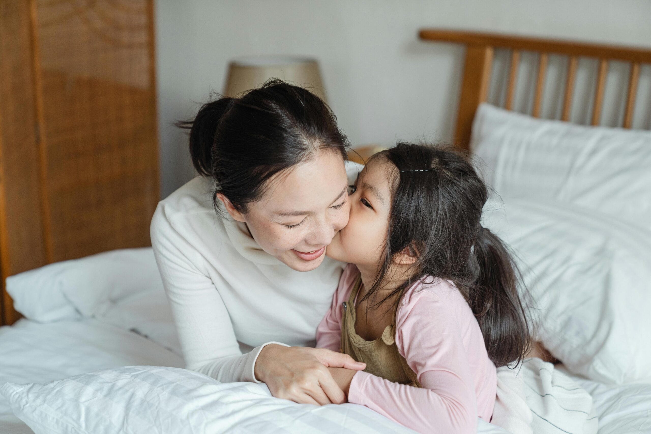 A loving mother and her daughter enjoy a cozy moment together on a bed, illustrating family bonding and affection.