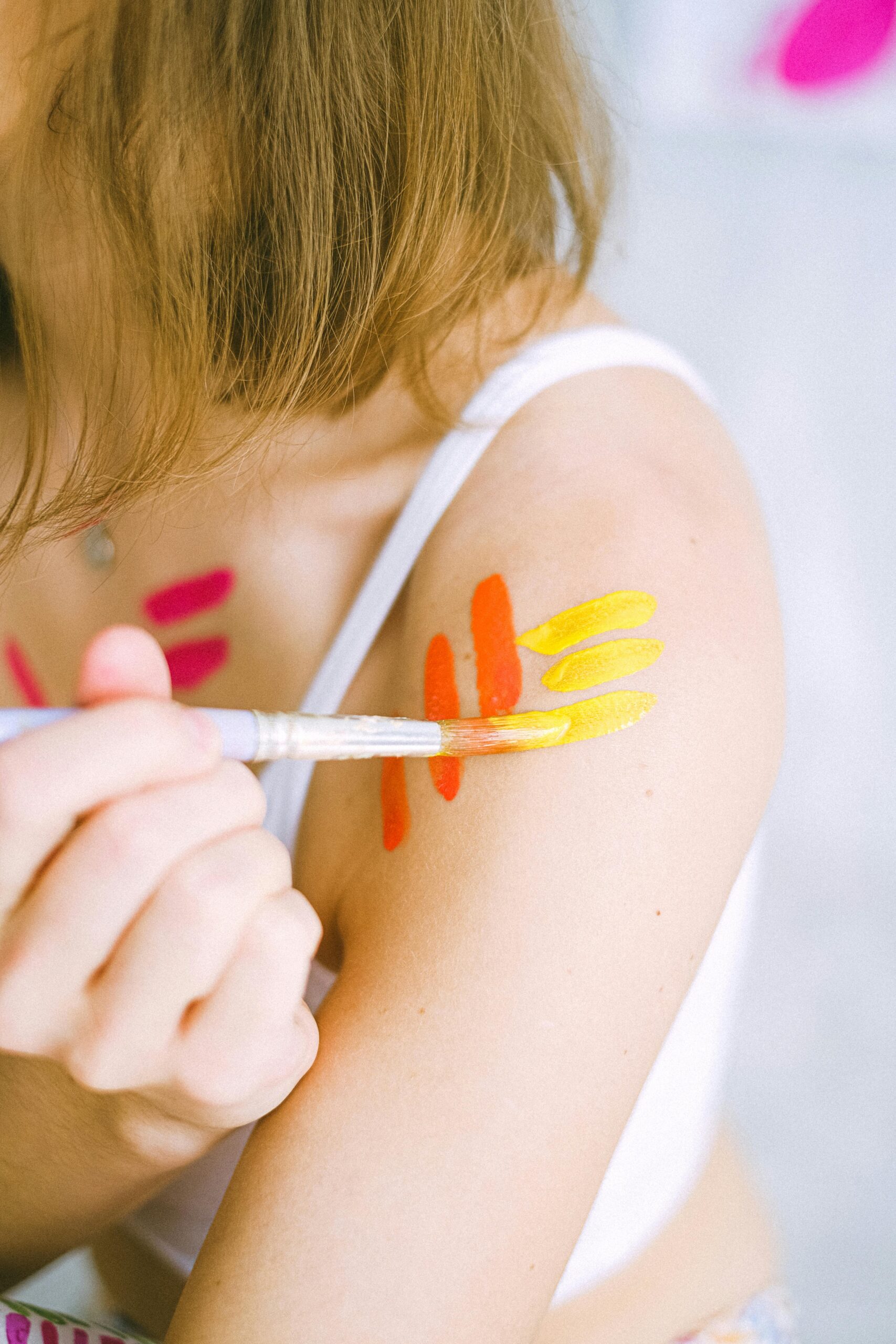 Close-up of a colorful body painting on a shoulder using a brush. Artistic and fun.