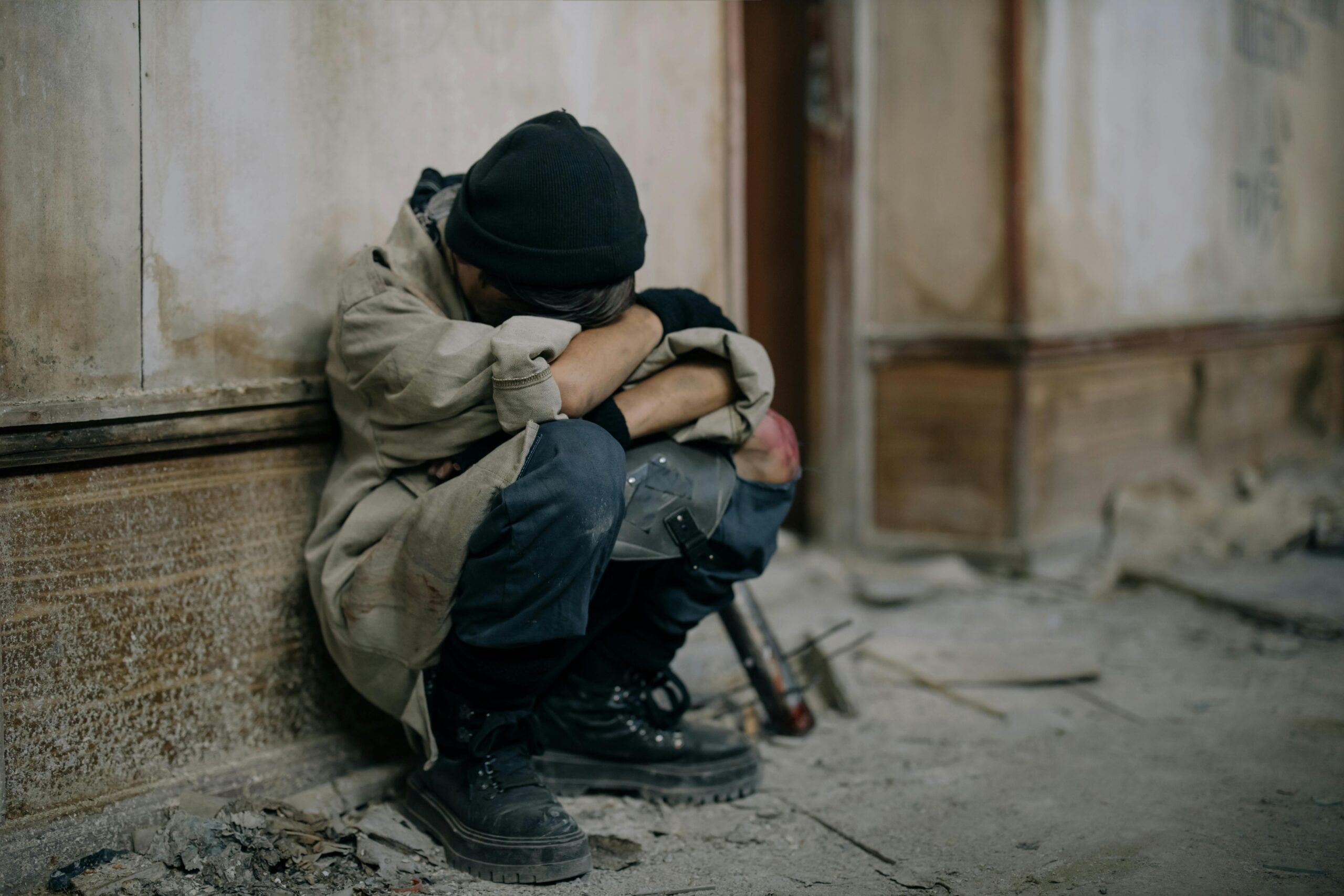 A young boy sits alone, appearing sad and forlorn, in an abandoned building setting.