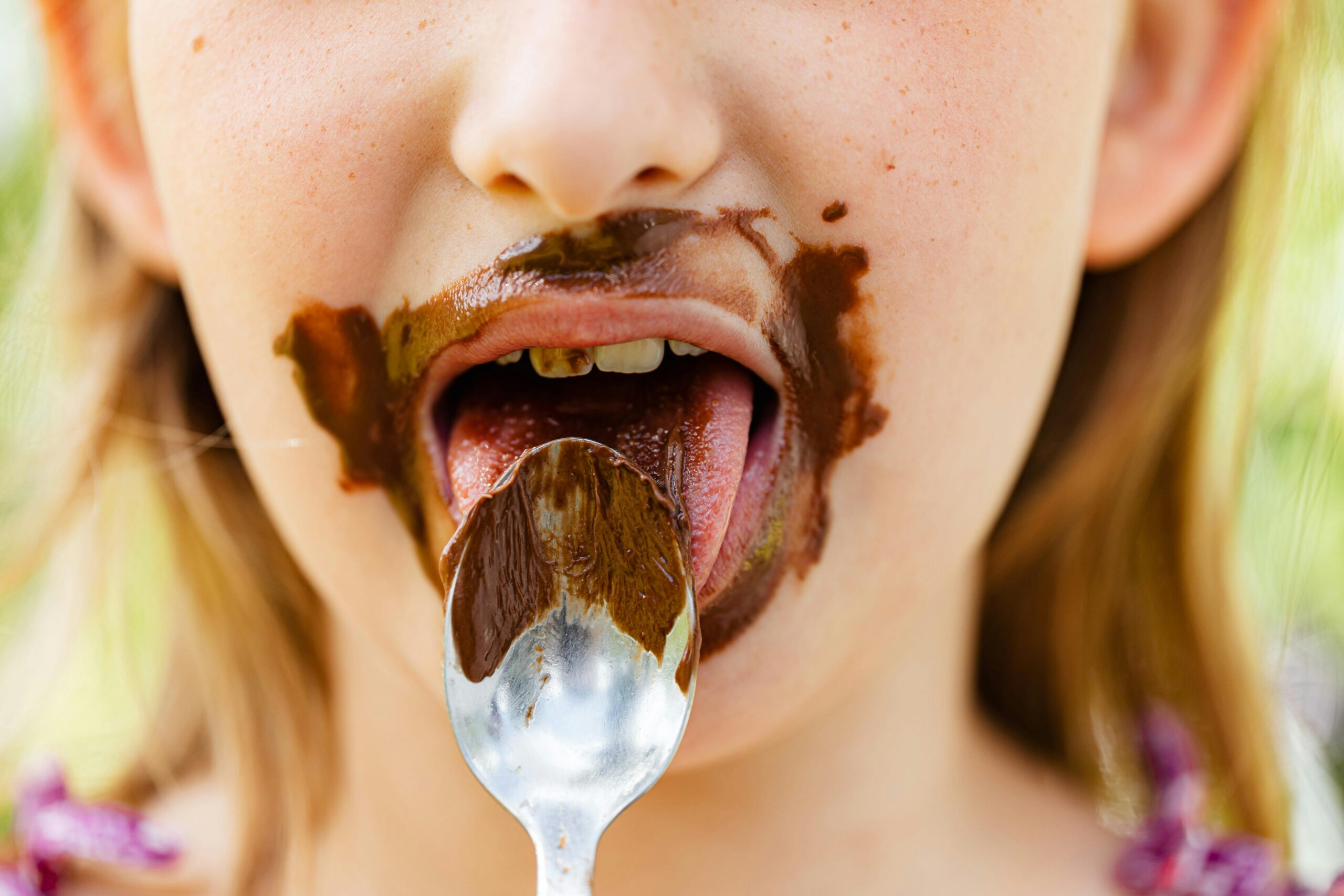 Close-up of a child eating chocolate with a spoon, messy and joyful.