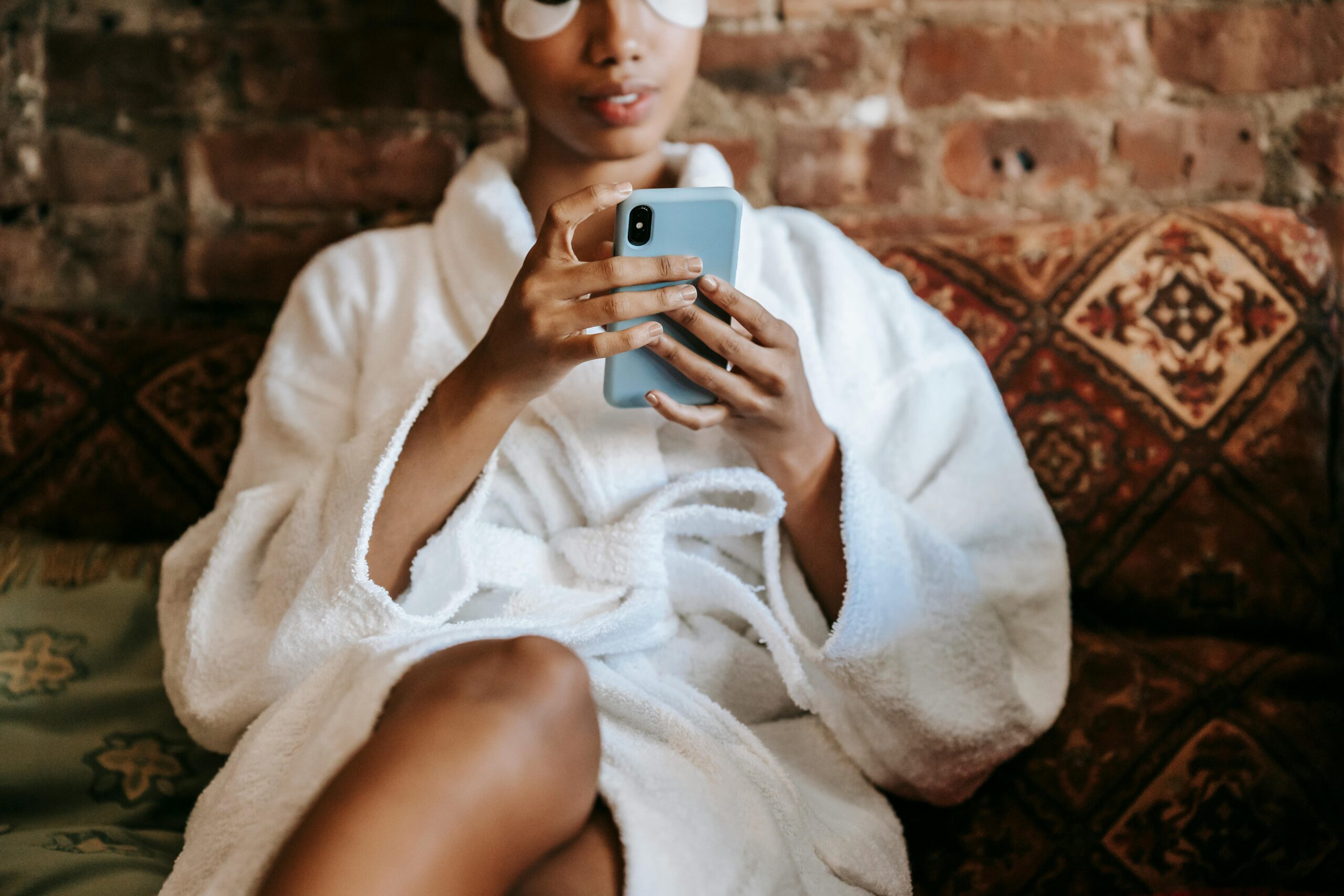 Young woman relaxing in a bathrobe with a smartphone indoors.