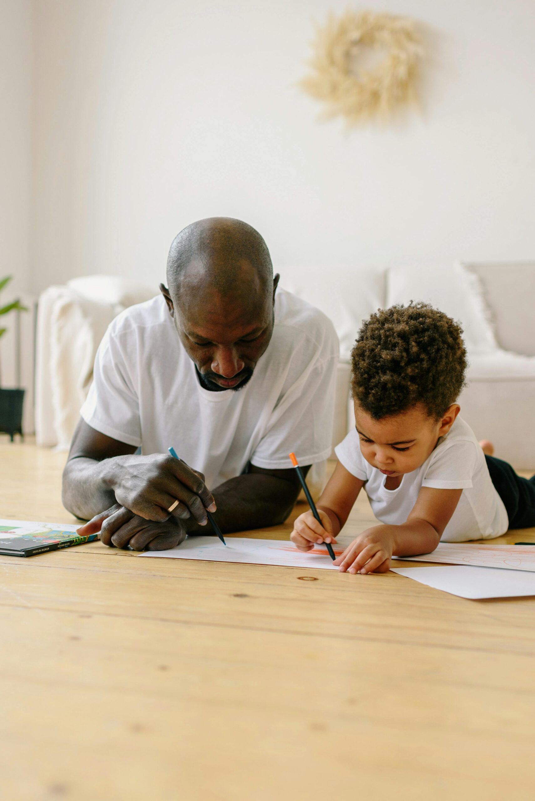 African American father and son drawing together on the floor, bonding time.