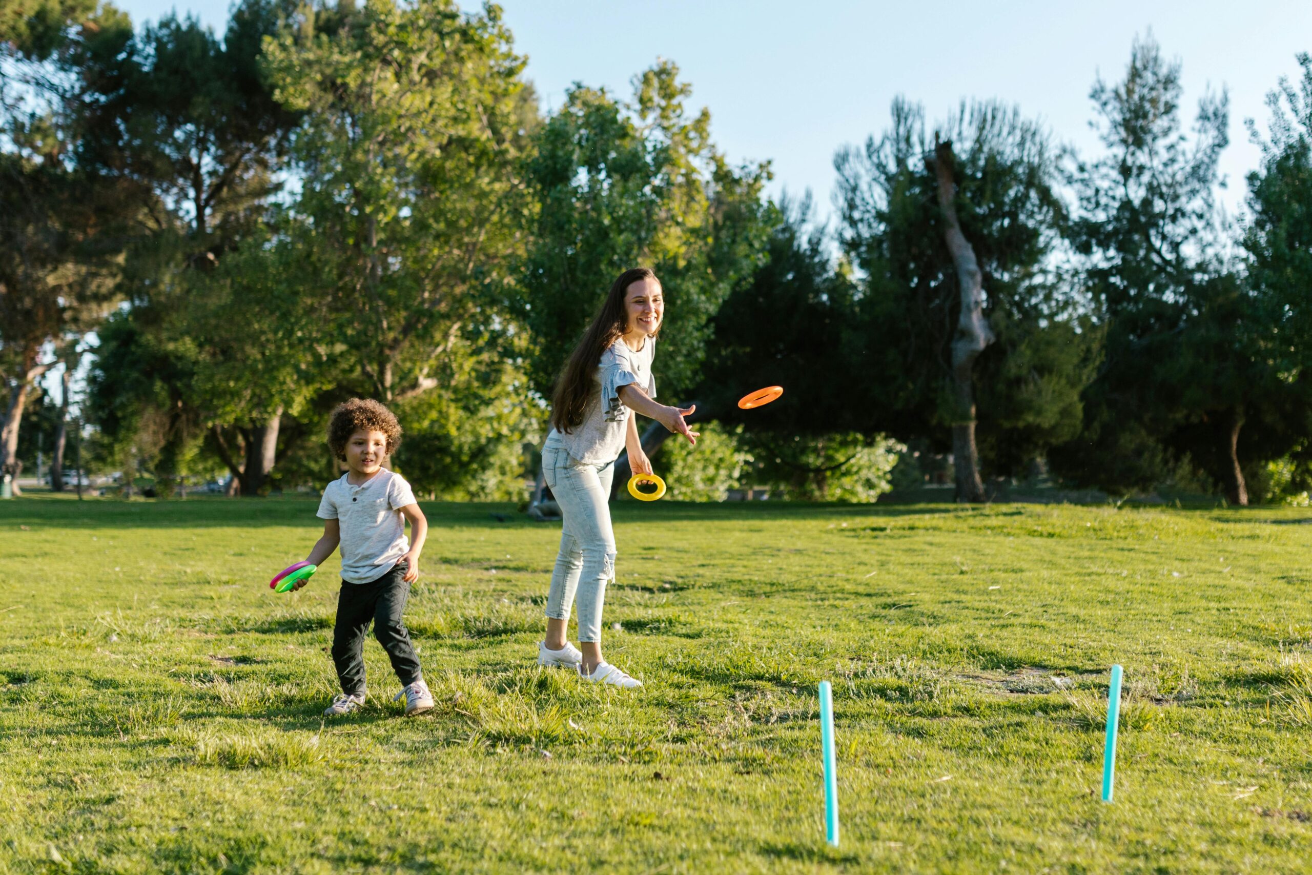 A joyful mother and son play a ring toss game in a sunny park, capturing family fun and bonding.