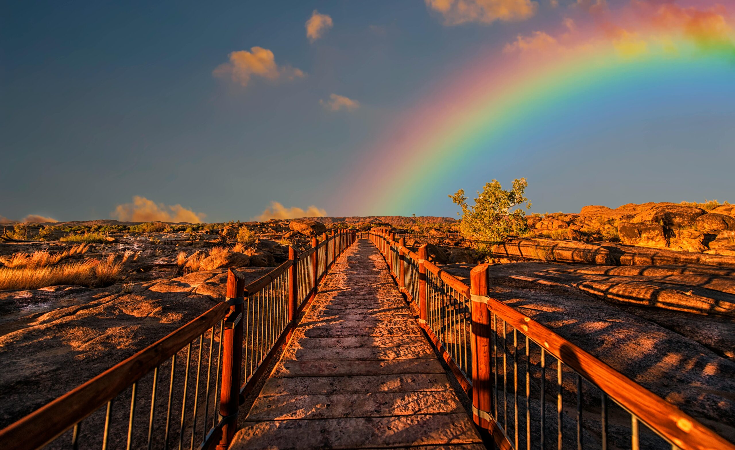 A scenic walkway with a rainbow arching across a vivid sky, perfect for outdoor photography.