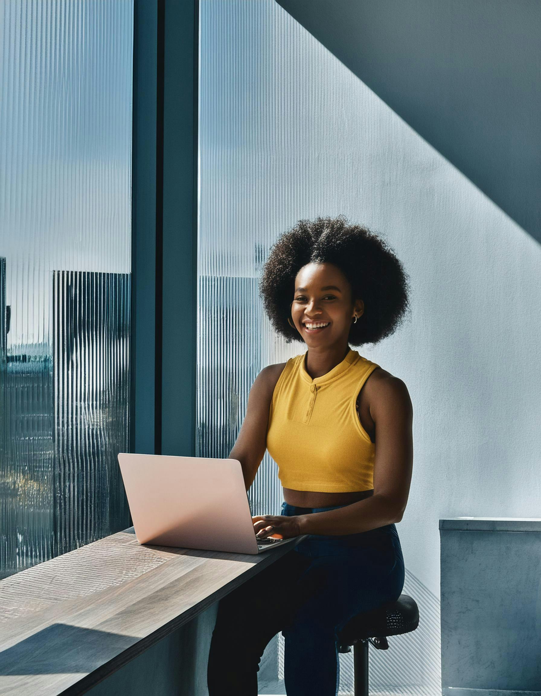 Bright portrait of a woman working on a laptop by a window in a modern office.