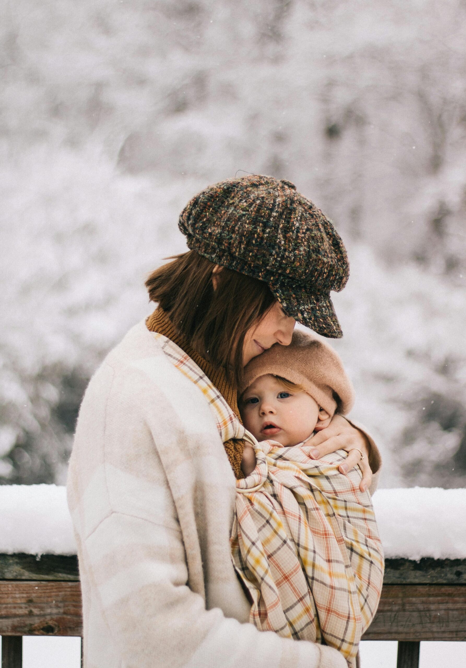 Heartwarming outdoor photo of a mother holding her baby in a snowy landscape, capturing a serene winter moment.