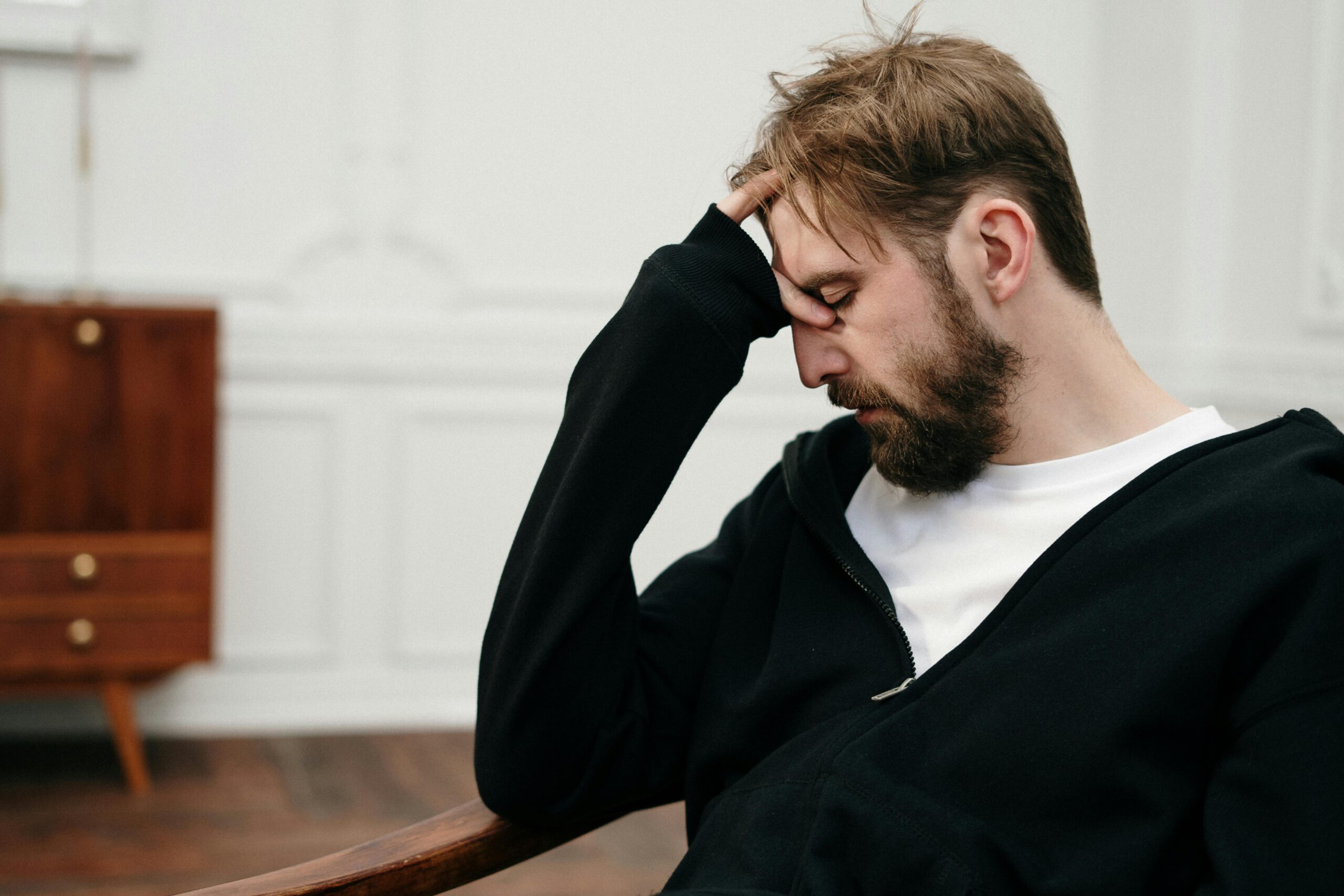 A man sits pensively with his hand on his face, capturing a moment of introspection and stress.