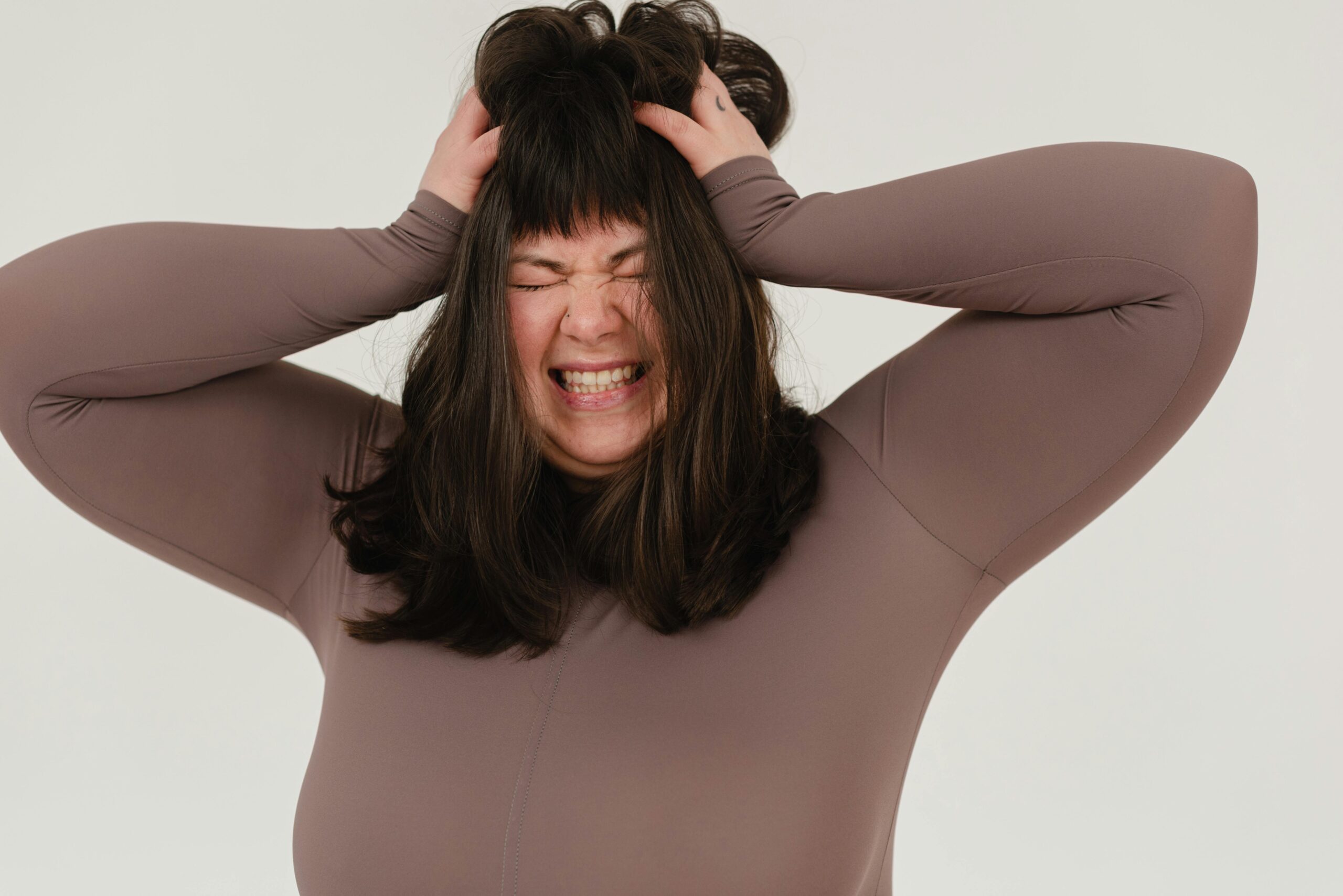 Young woman expressing frustration with hands on head in a studio shoot.